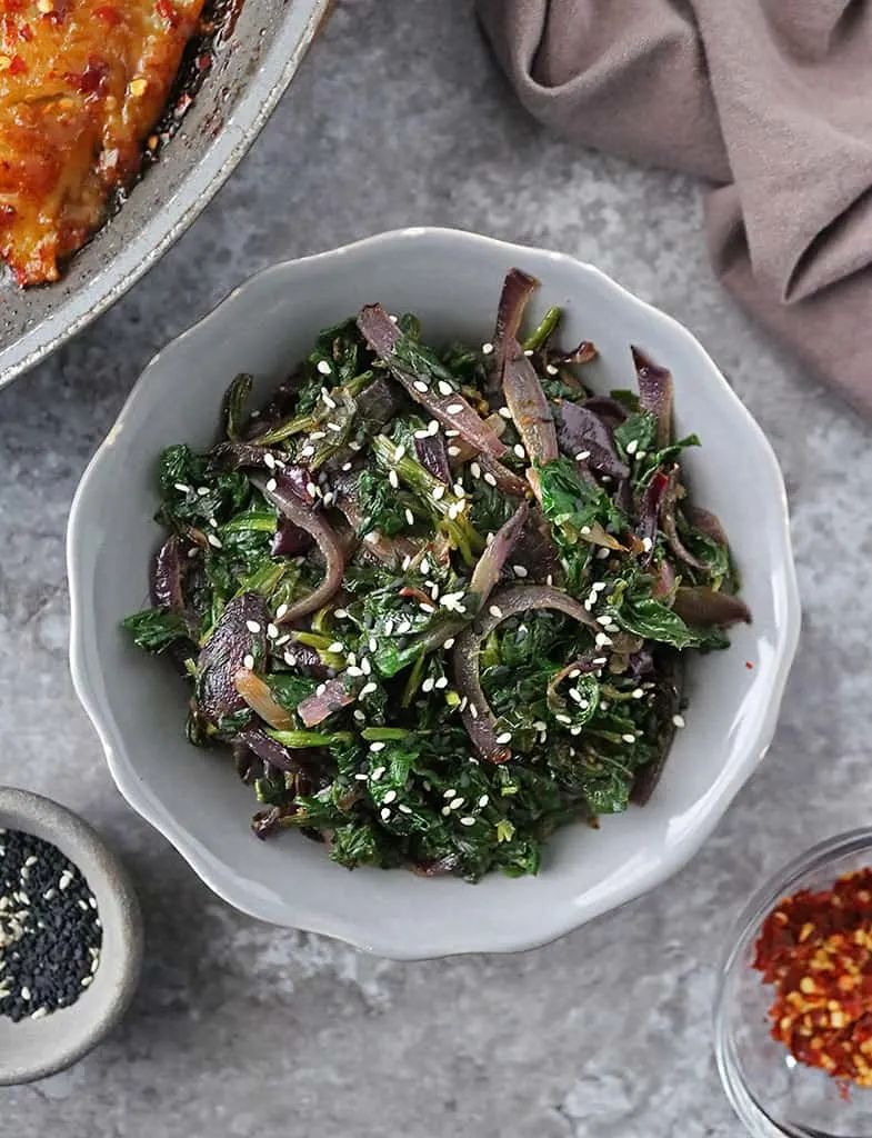 a gray bowl with Sauteed Soy Sesame Spinach & Onions