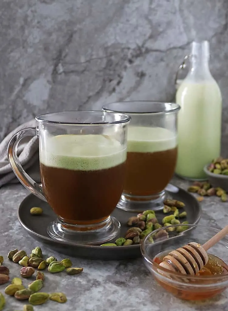 Add in strong brewed coffee to frothed pistachio milk and honey in mug