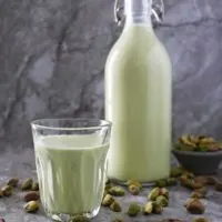 A bottle and a glass cup of Easy plant-based - clean keto Pistachio milk