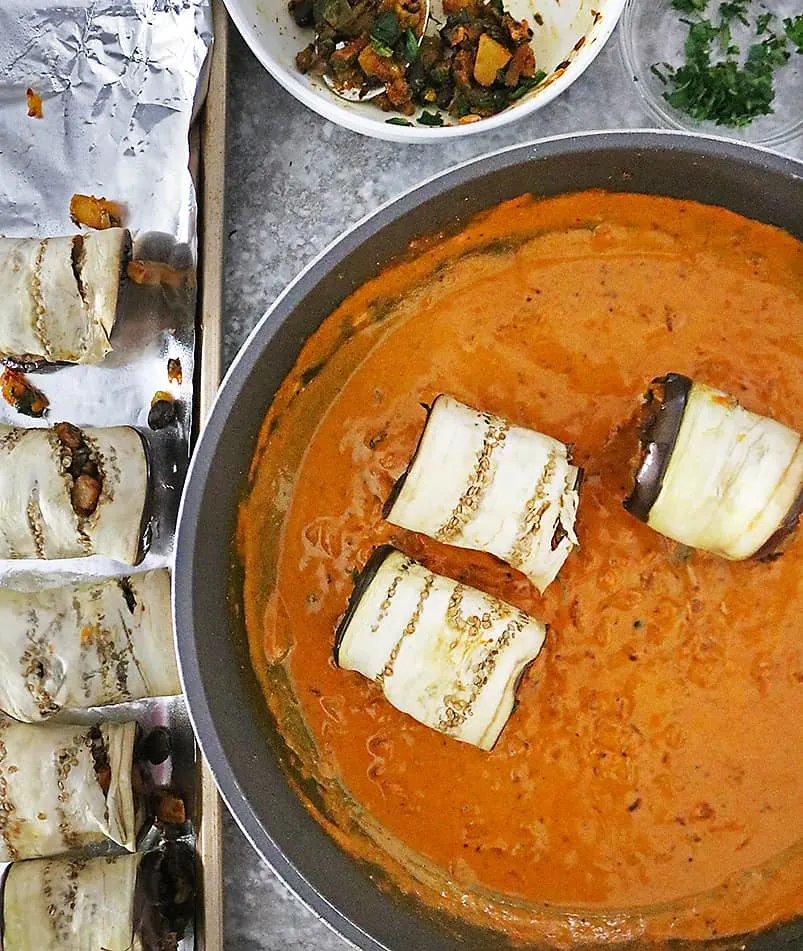 Placing stuffed eggplant slices in rich spicy sauce