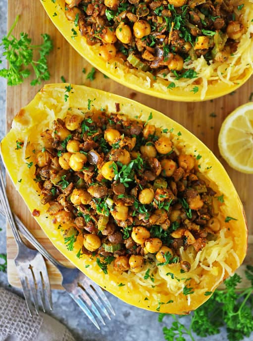 Two spaghetti squash halves baked and stuffed with a spicy lentil chickpea stuffing.