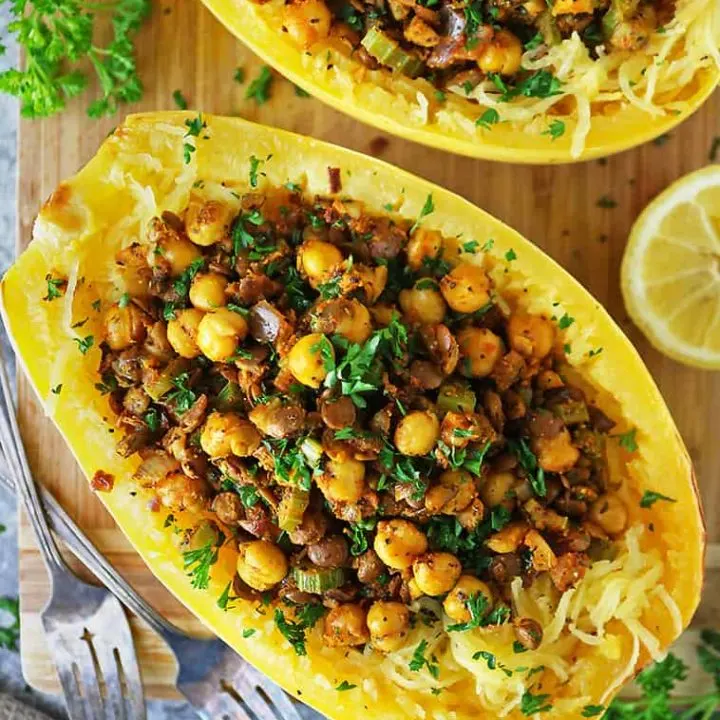 Two spaghetti squash halves baked and stuffed with a spicy lentil chickpea stuffing.