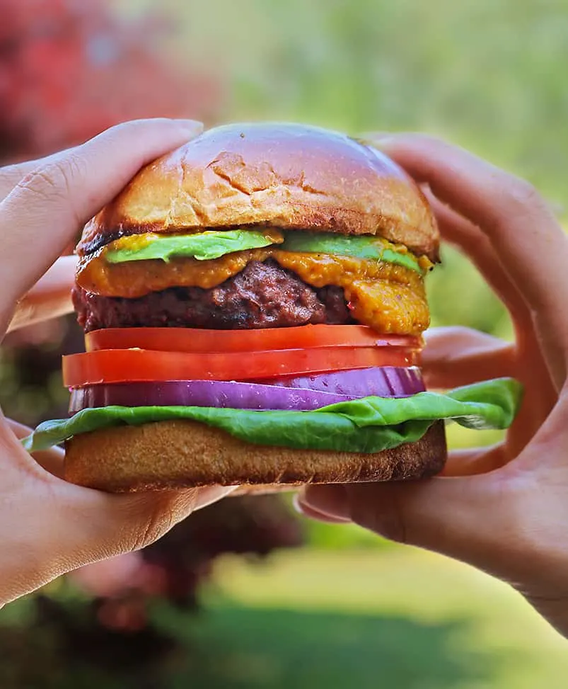 Taking a bite of plant-based Beyond Meat Burger with spicy mango sauce