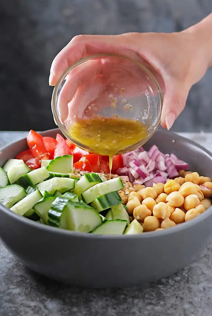 Pouring over Garlic Vinaigrette onto easy chickpea salad