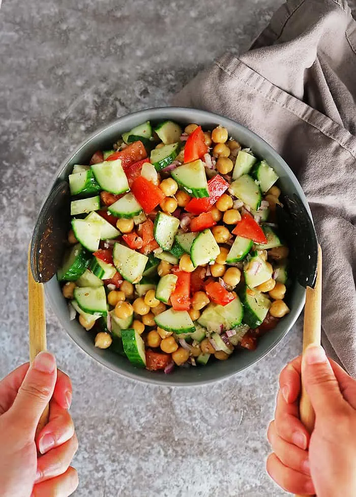 Tossing a bowl of Chickpeas, tomatoes, red onion, and cucumber are enveloped in a garlic zata’ar vinaigrette in this tasty and easy vegan chickpea salad.