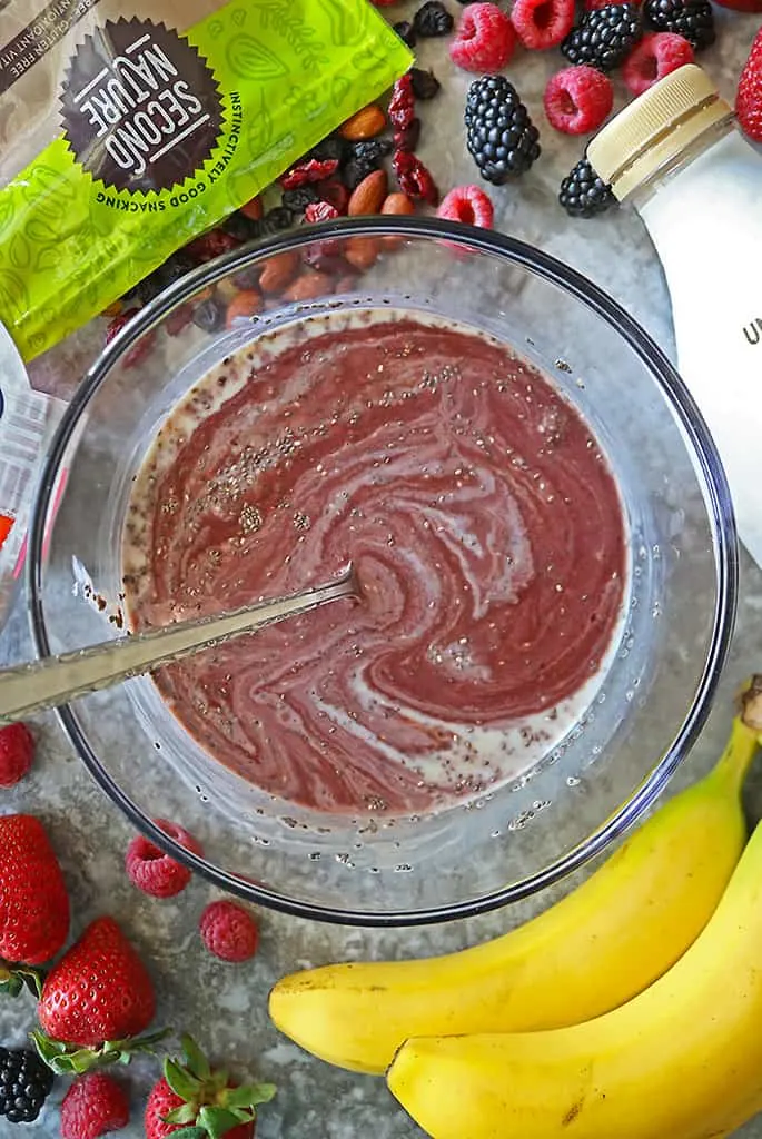 Mixing together Ripple dairyfree milk, sambazon, and chia seeds in a large glass bowl