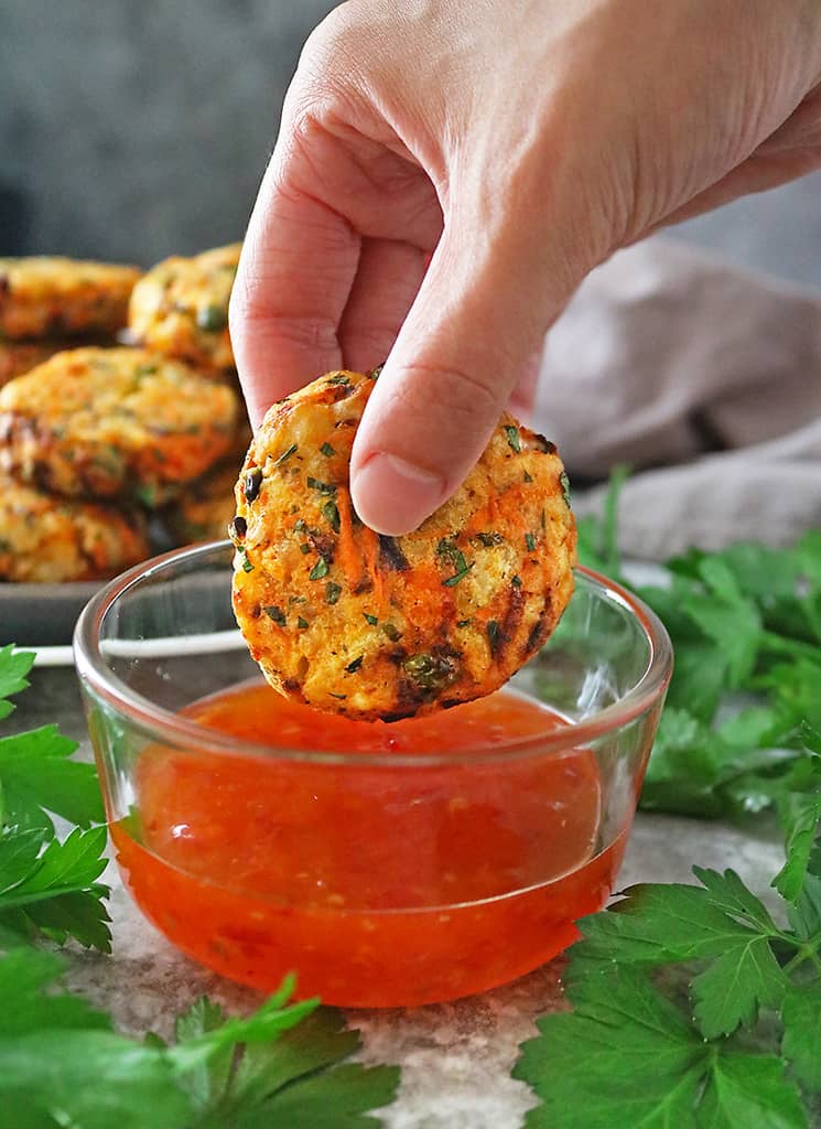 Photo showing spicy veggie fritters being dipped into Franks RedHot original sauce.