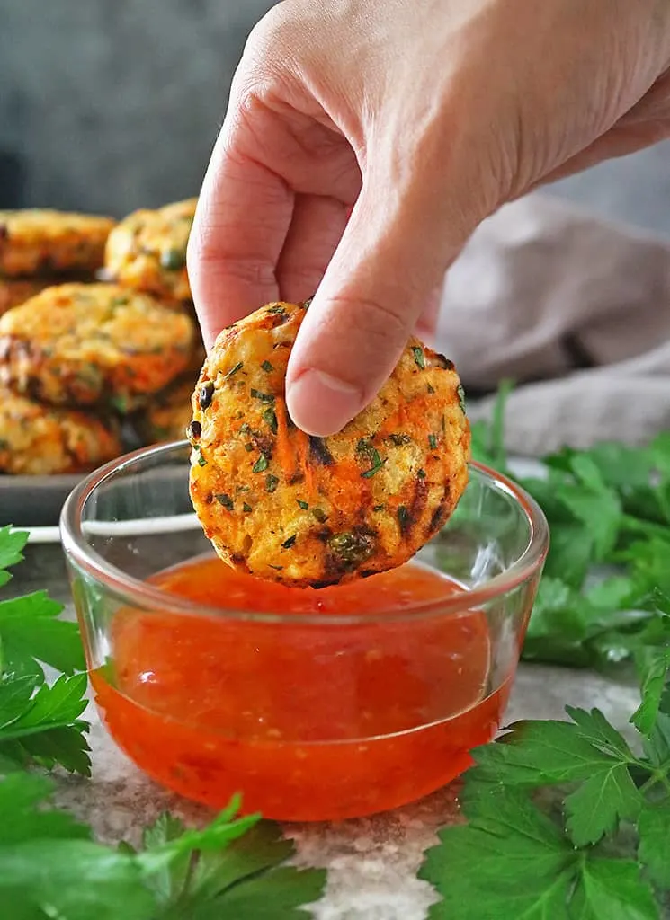 Photo showing spicy veggie fritters being dipped into Franks RedHot original sauce.