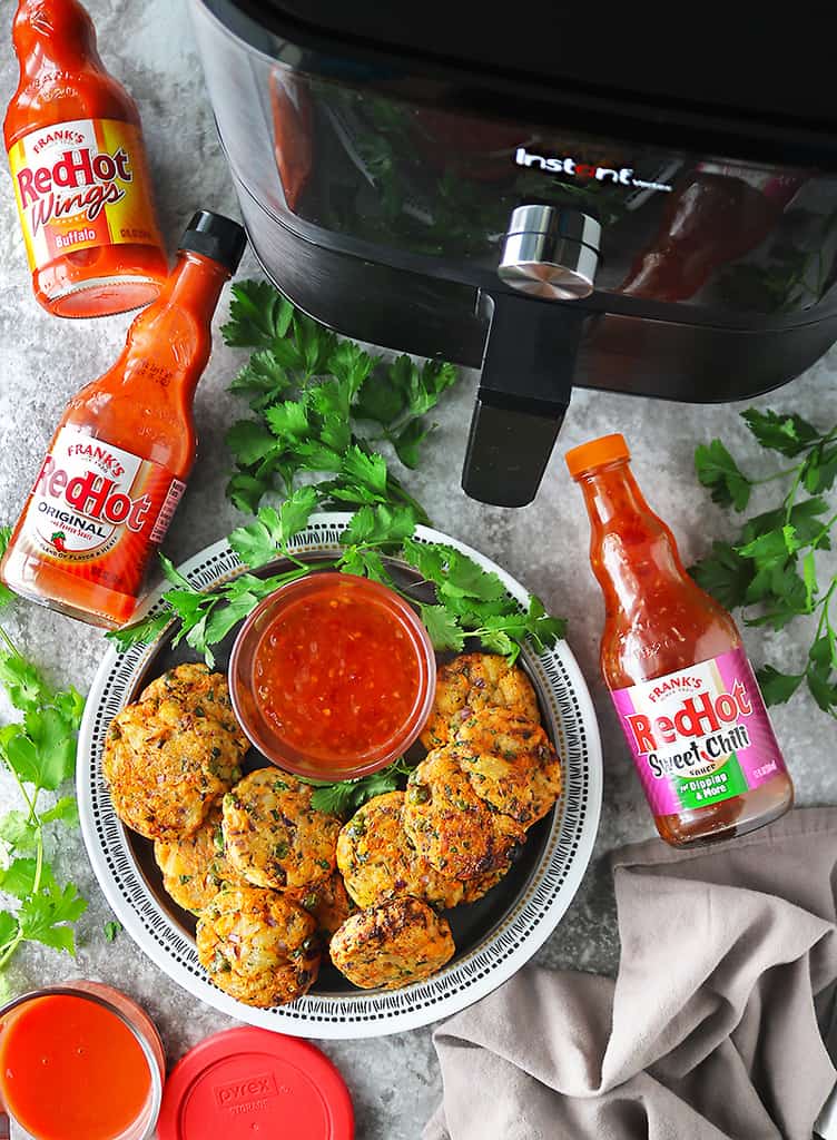 Easy Air-fried vegetable fritters laid out on a table with a variety of Franks red hot sauce.