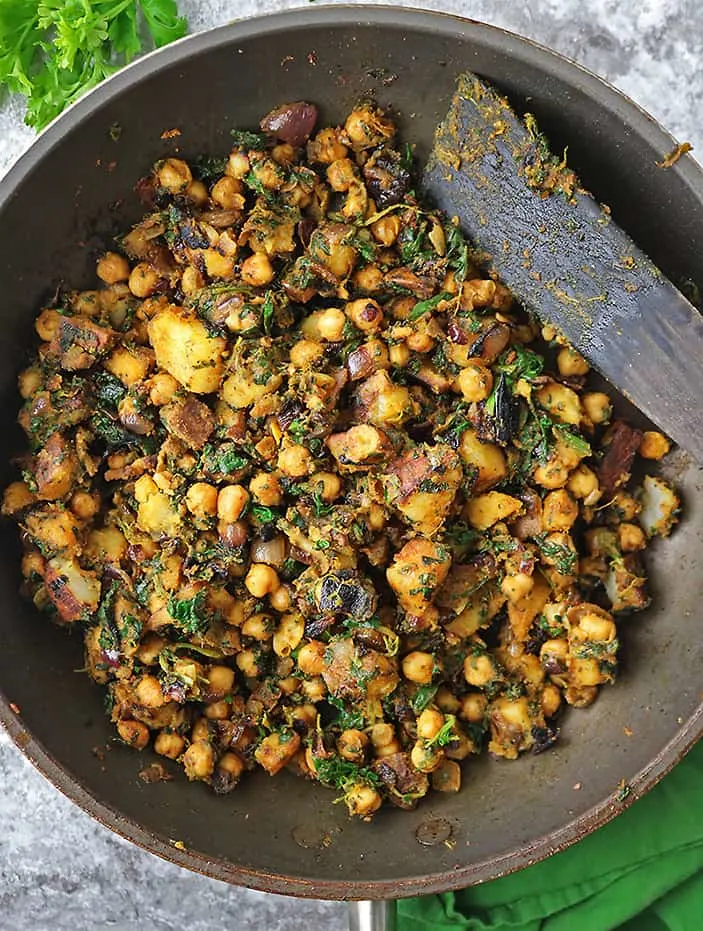 Sauteing together potatoes, chickpeas, spinach, ginger, garlic, onion, and spices to make a wholesome nutritious and flavorful dish that is satisfying and so tasty.