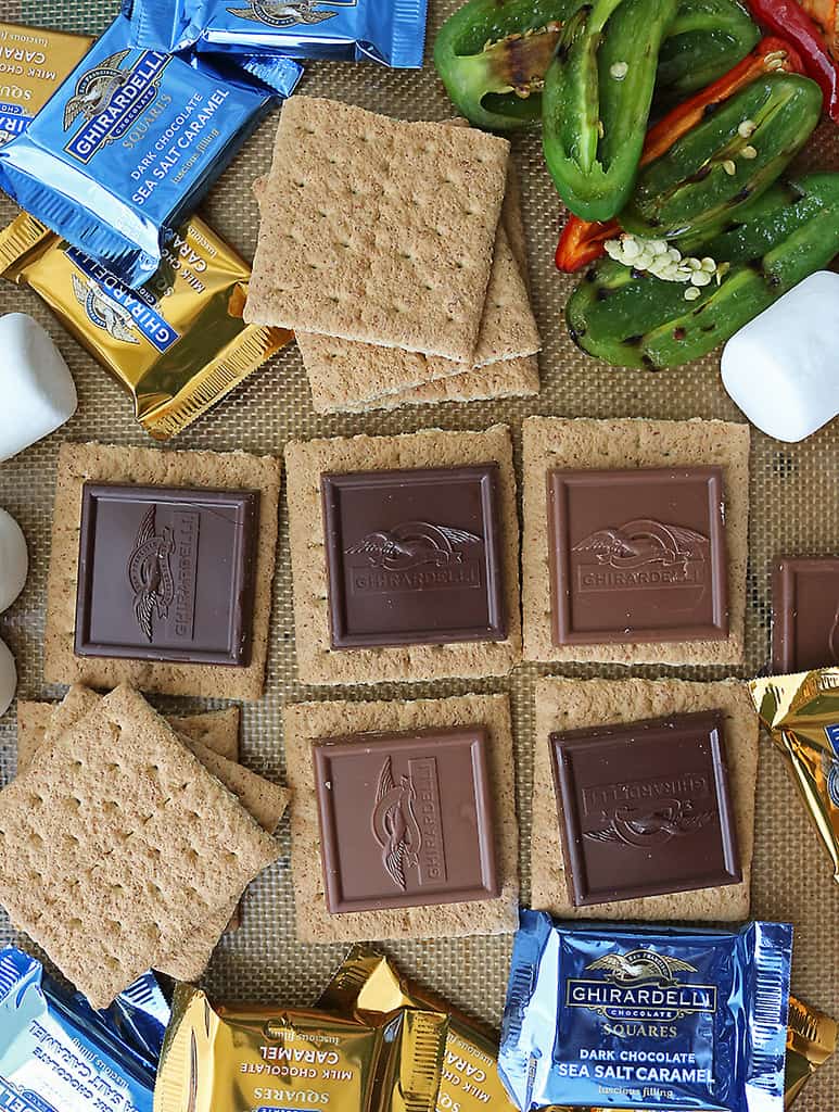 Adding graham crackers, chocolate squares to baking tray to make baked s'mores.