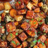 The most crispy Easy Sheet Pan Spicy Tofu and veggies on a sheet pan with BBQ sauce.