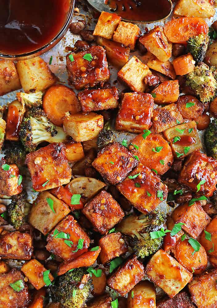 The most crispy Easy Sheet Pan Spicy Tofu and veggies on a sheet pan with BBQ sauce.