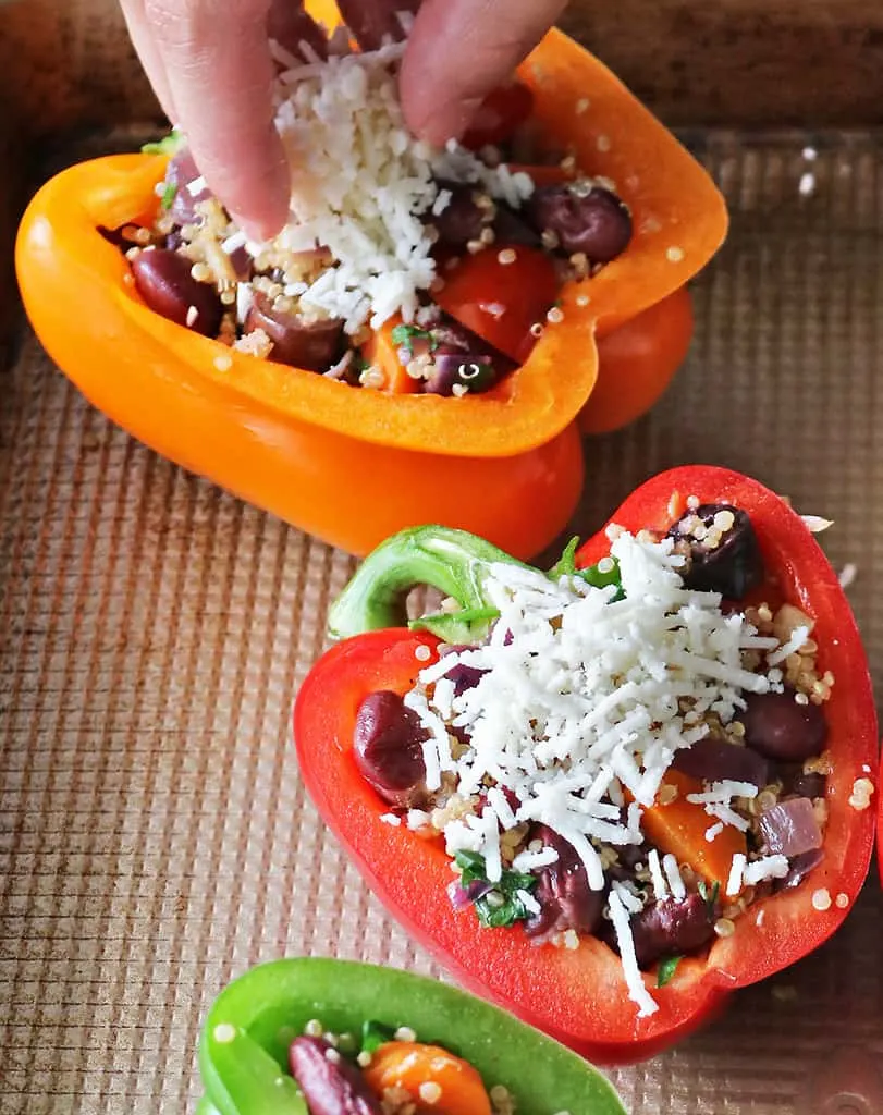 Topping vegan stuffed bell peppers with vegan cheese