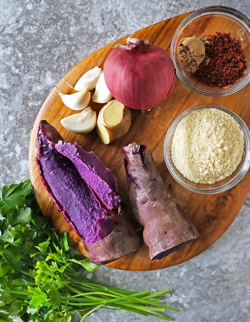 Ingredients to make purple sweet potato fritters aka one-eyed purple people eater on a wooden board.