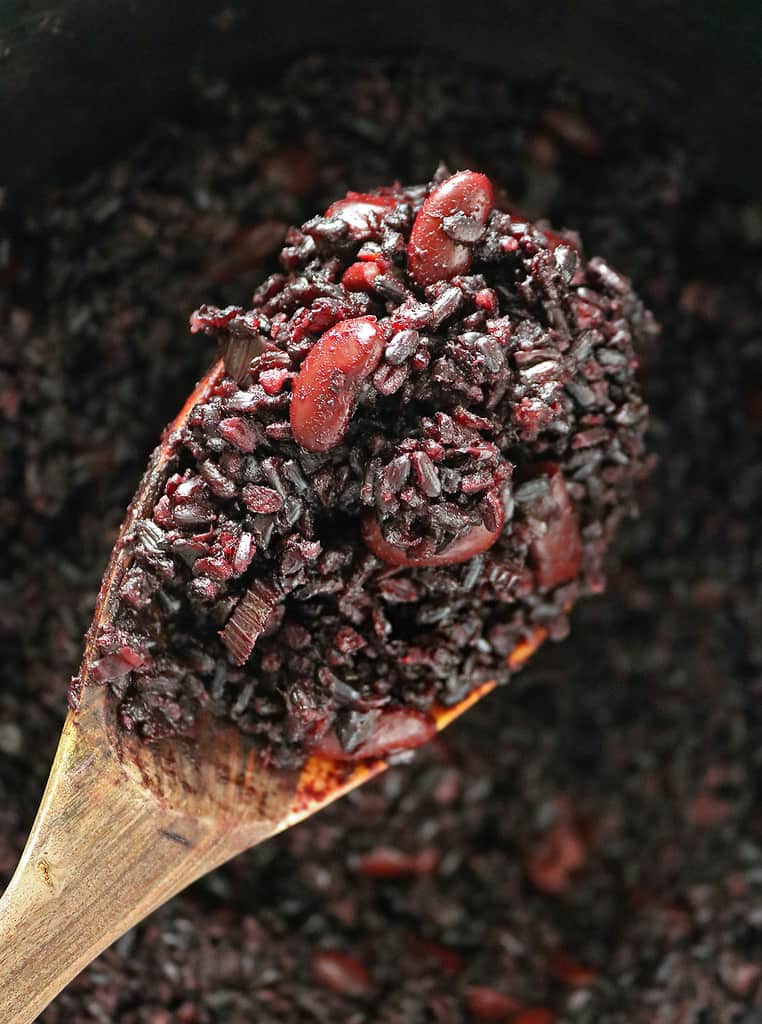 A spoonful of black rice and kidney beans out of the pan