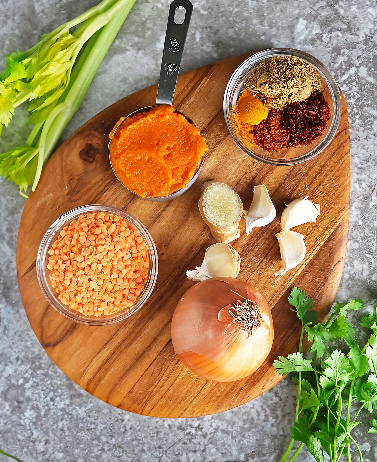 Ingredients to make pumpkin lentil curry on a wood board.