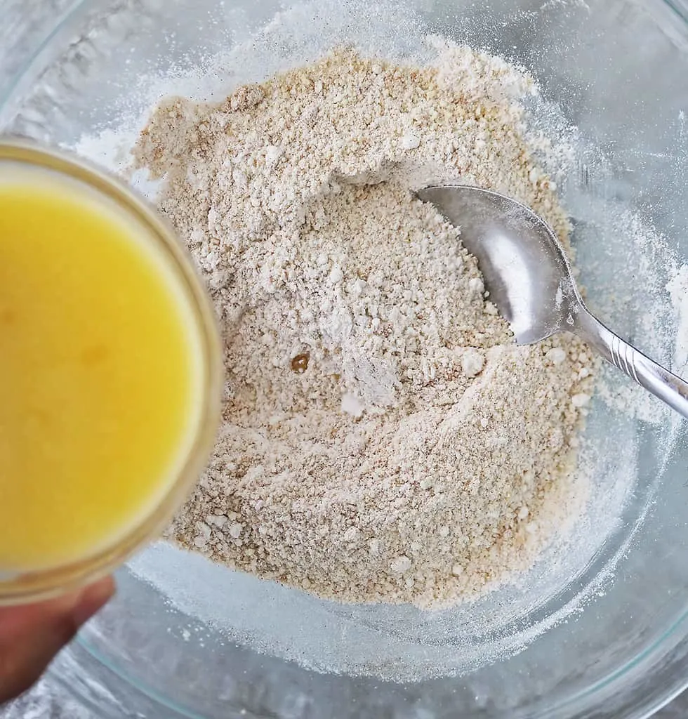 Mixing wet ingredients together with dry ingredients to make pecan cranberry cookies