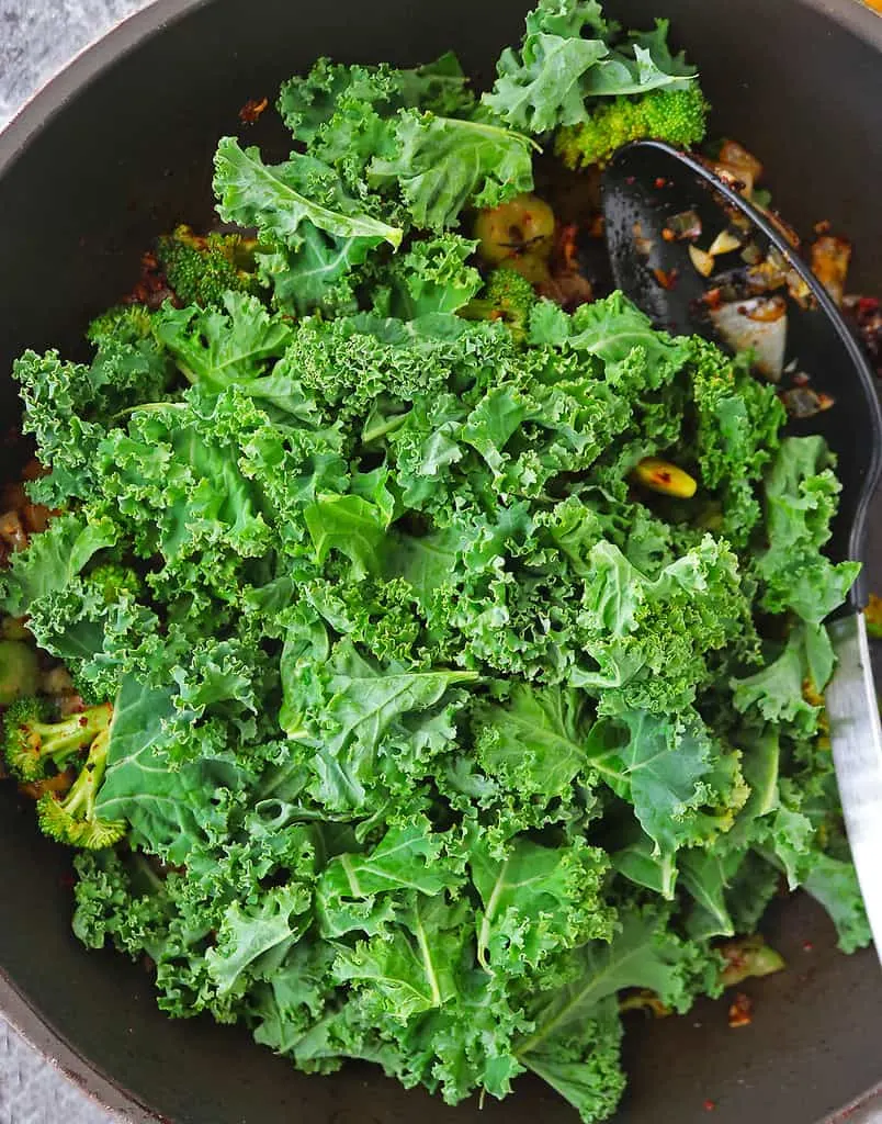 Adding kale to the sauteed ingredients