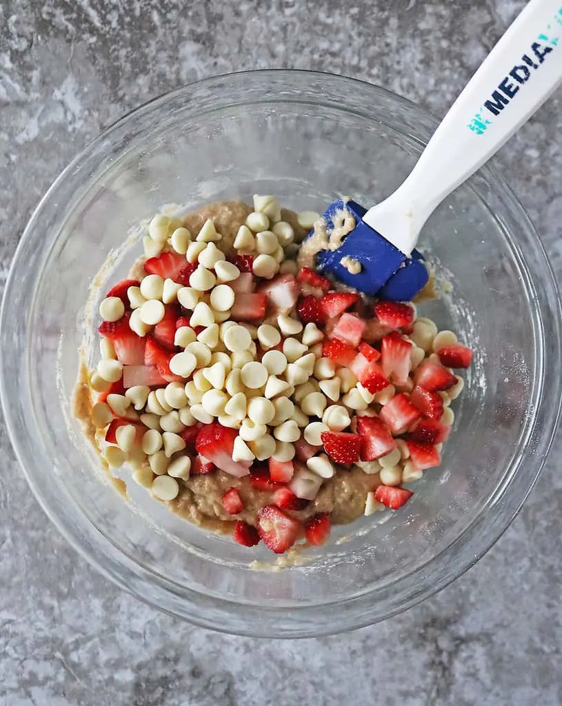 Mixing in Strawberries and white chocolate to make Muffin Tops.