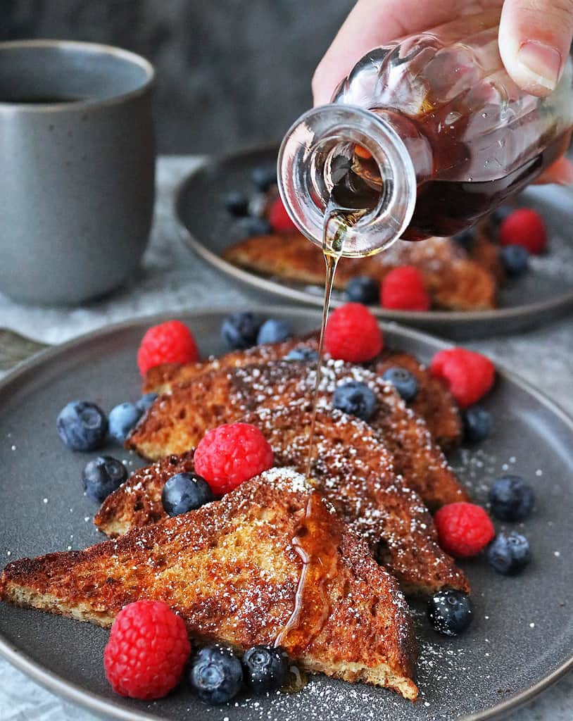 My Favorite French toast made without eggs on a grey plate with maple syrup.