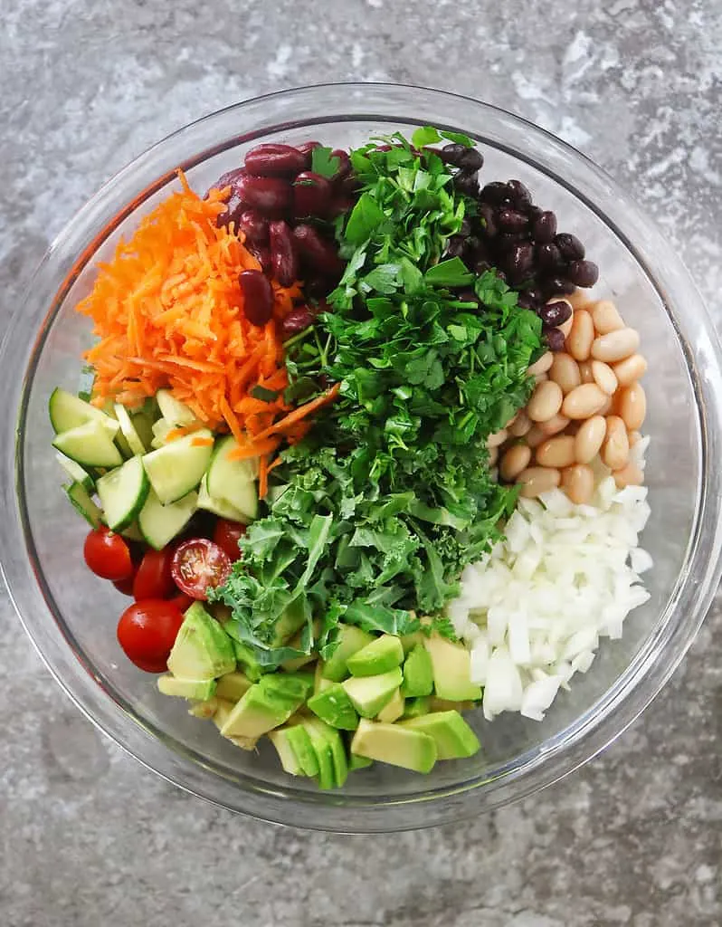 Adding ingredients to a bowl to make the best bean salad ever