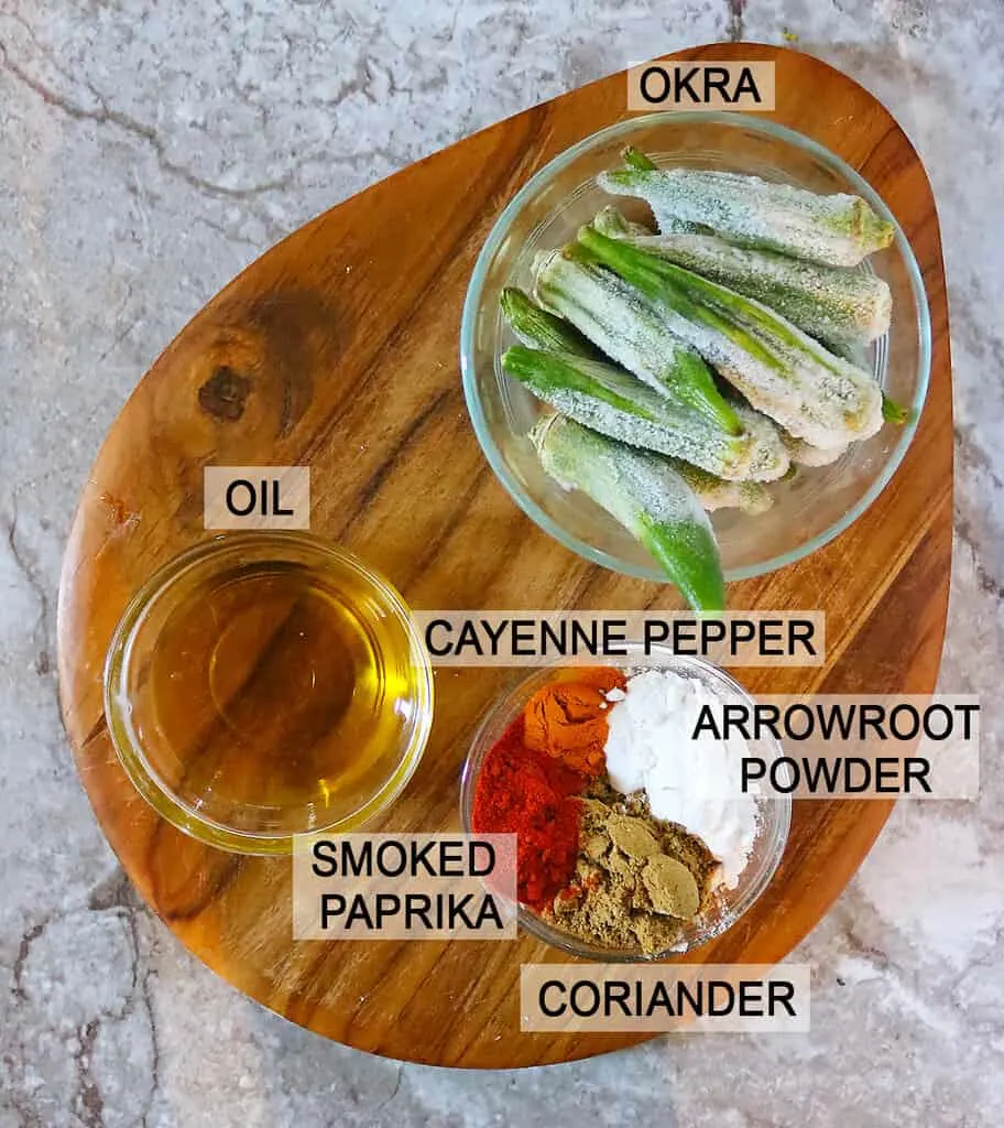 The 6 Ingredients to make easy baked okra placed on a wooden board.