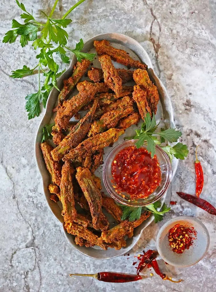 oven baked spicy okra placed on a silver serving tray.