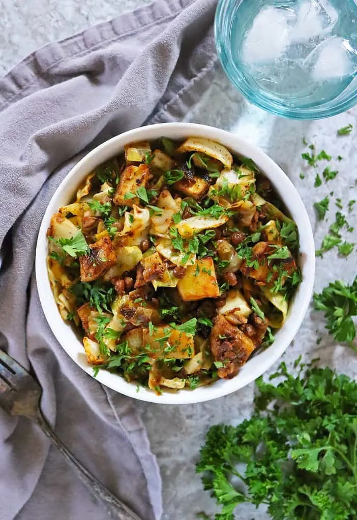 This easy cabbage potato lentil recipe is served in a bowl with a grey napkin