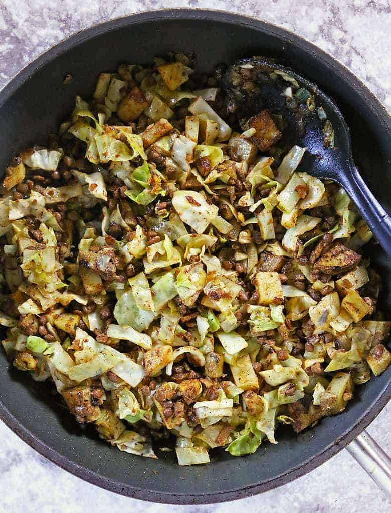 Making cabbage potato lentil saute in a large pan