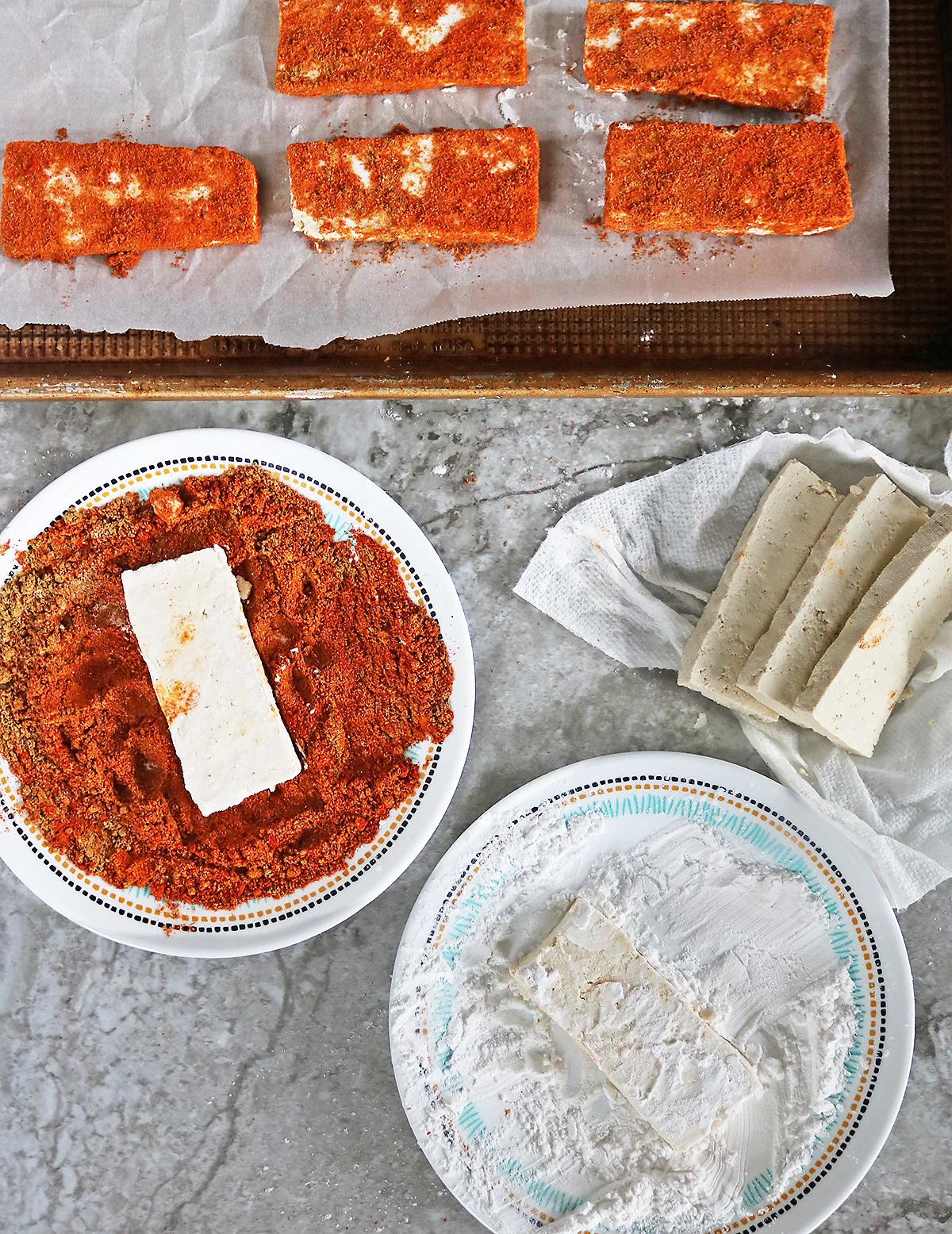 prepping tofu by dusting it with arrowroot powder and then a spice blend getting it ready to bake