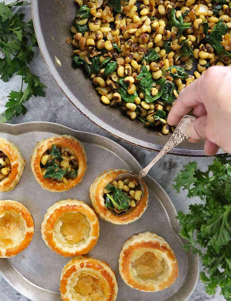 Filling puff pastry baskets with Black Eyed Peas and greens