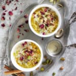 Dairy-free Gluten-free Oat kheer or Oat pudding in two white bowls with rose petals and pistachios scattered around.