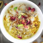 A white bowl with Oat pudding made with saffron, rose water and pistachios