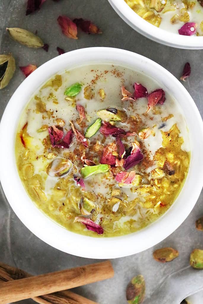 A white bowl with Oat pudding made with saffron, rose water and pistachios