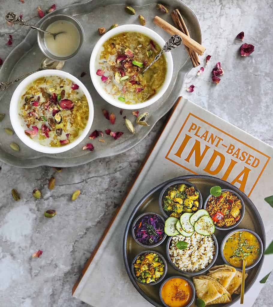 two bowls of oat pudding with saffron, rose petls, pistachios and cinnamon next to Plant-based India cookbook by Sheil Shukla