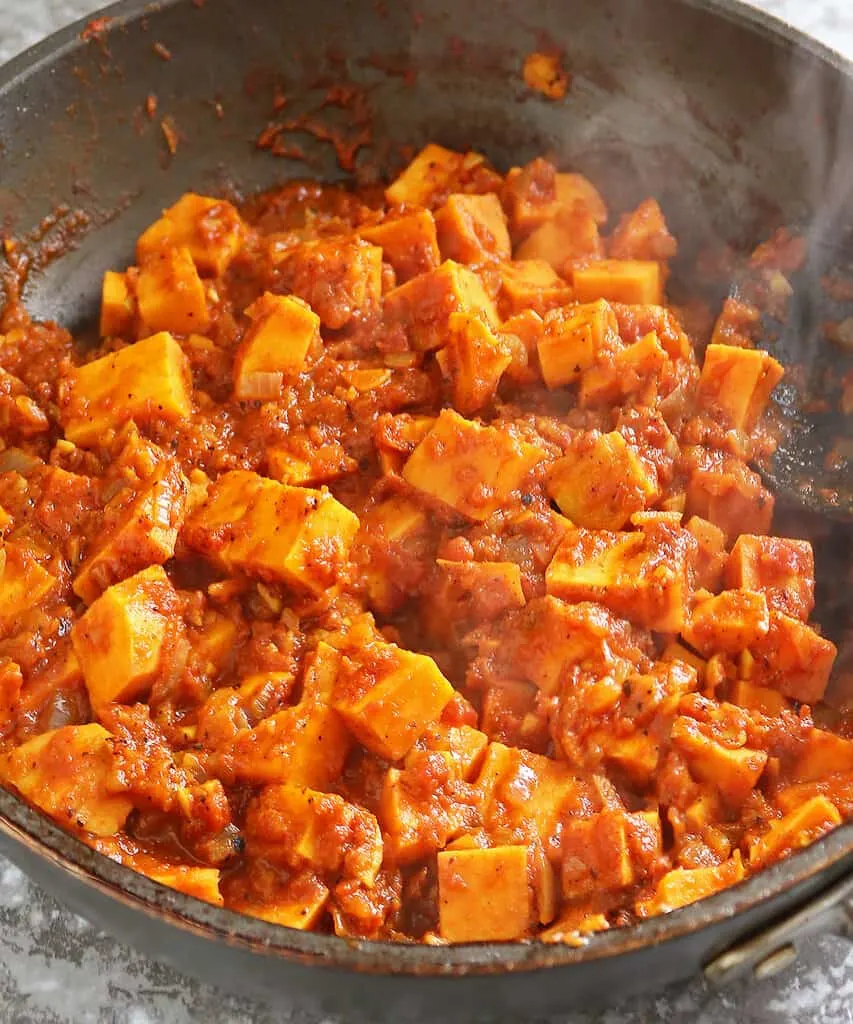 Roasting sweet potatoes with onion, ginger, garlic, and spices - the beginning of sweet potato curry. 