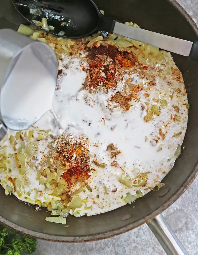 Adding coconut milk to onions ginger garlic spices