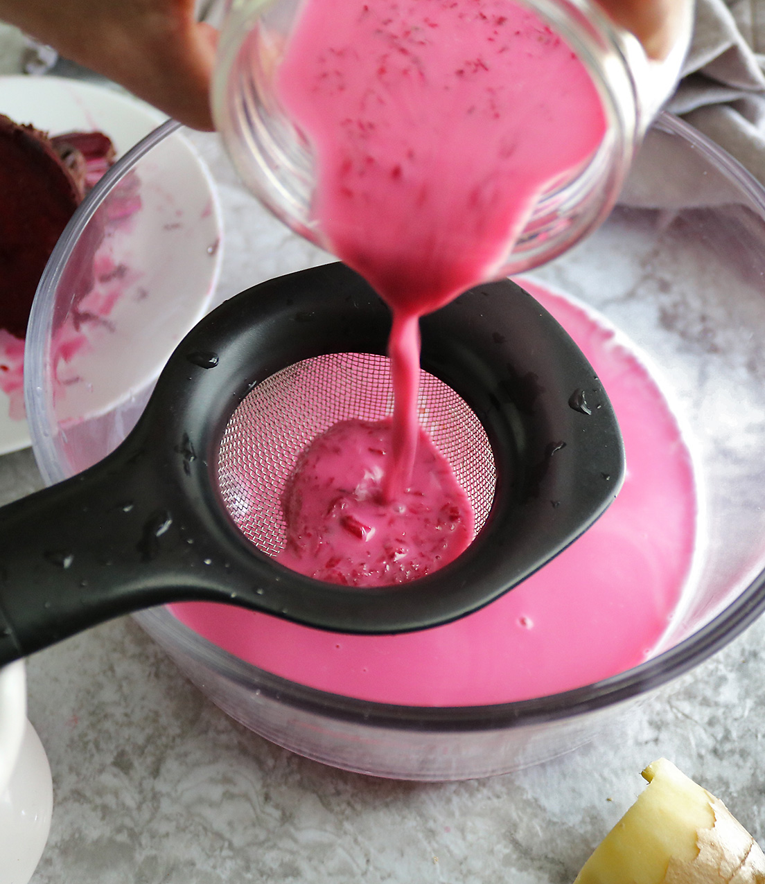 Straining beet milk to make pink chia pudding.