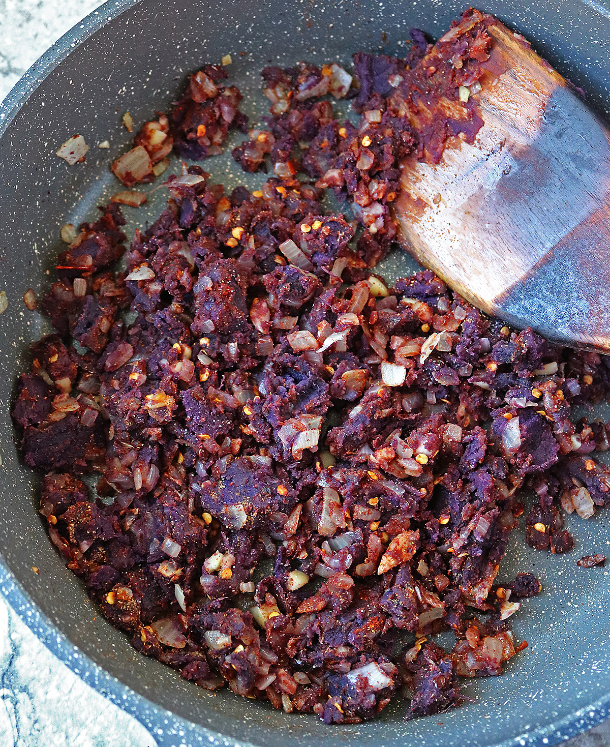 Adding purple sweet potatoes and spices to onions, ginger, garlic