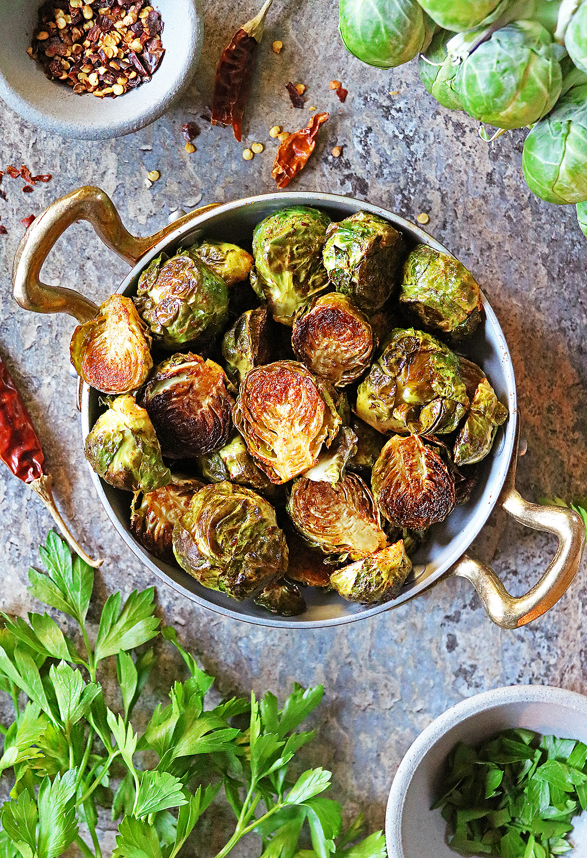 My favorite Oven Roasted Brussels sprouts with Berbere in a golden skillet with chili flakes and cilantro garniches.