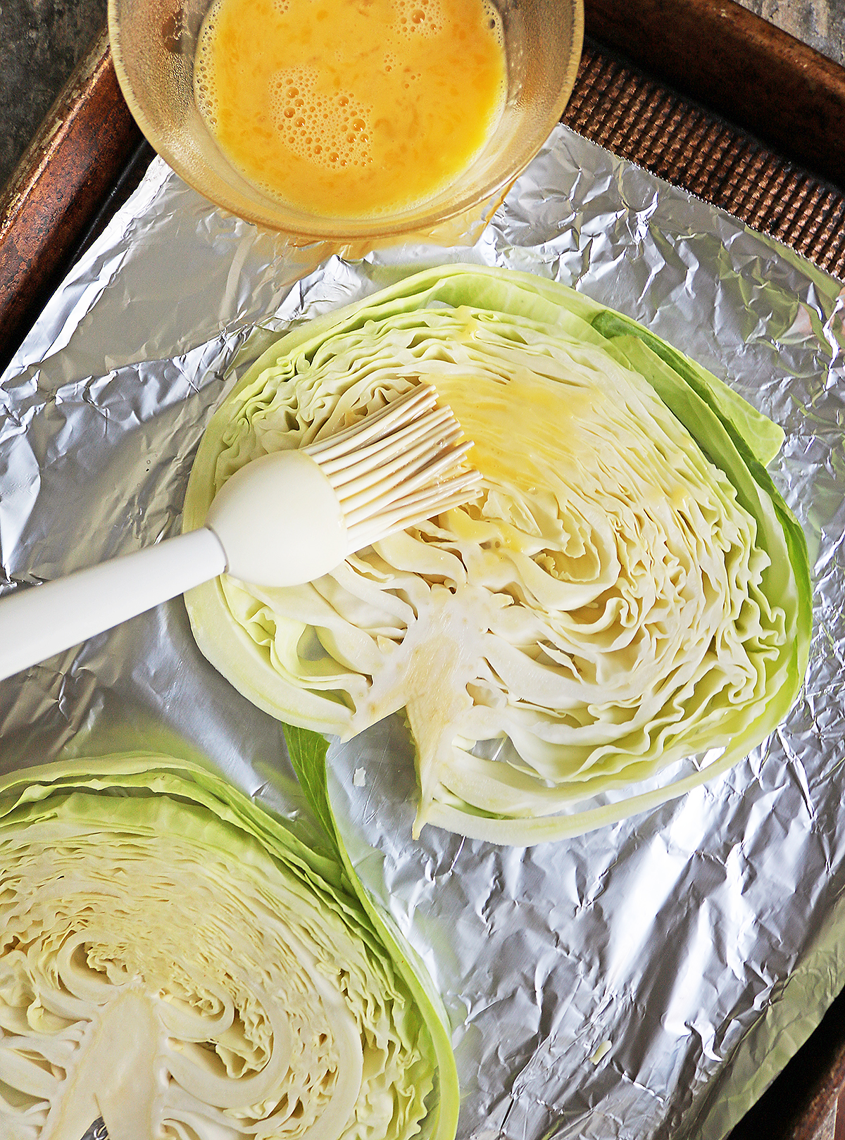Brushing on egg wash onto the cabbage steaks