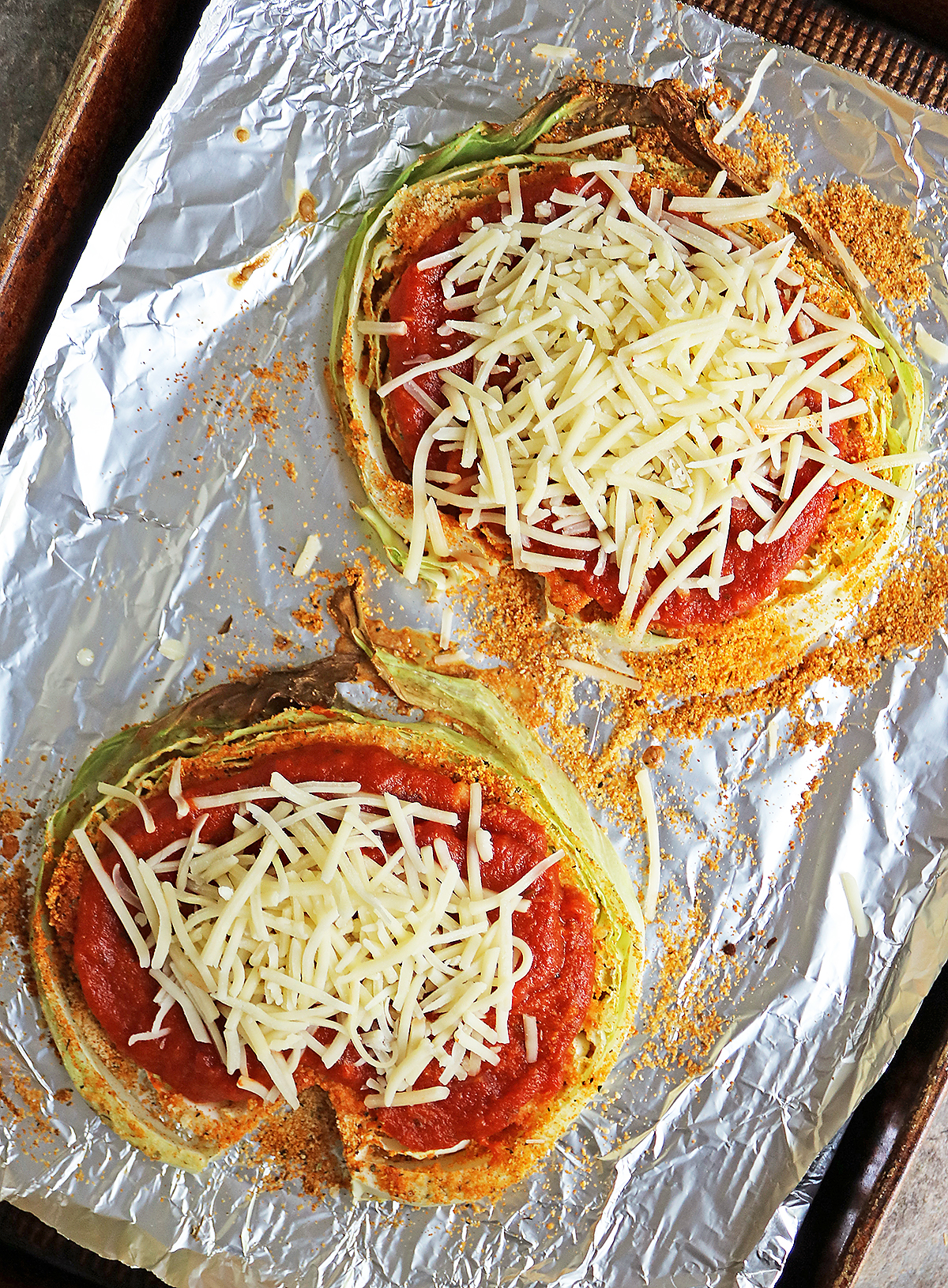 Cabbage slices with almond flour coating topped with tomato sauce and cheddar cheese