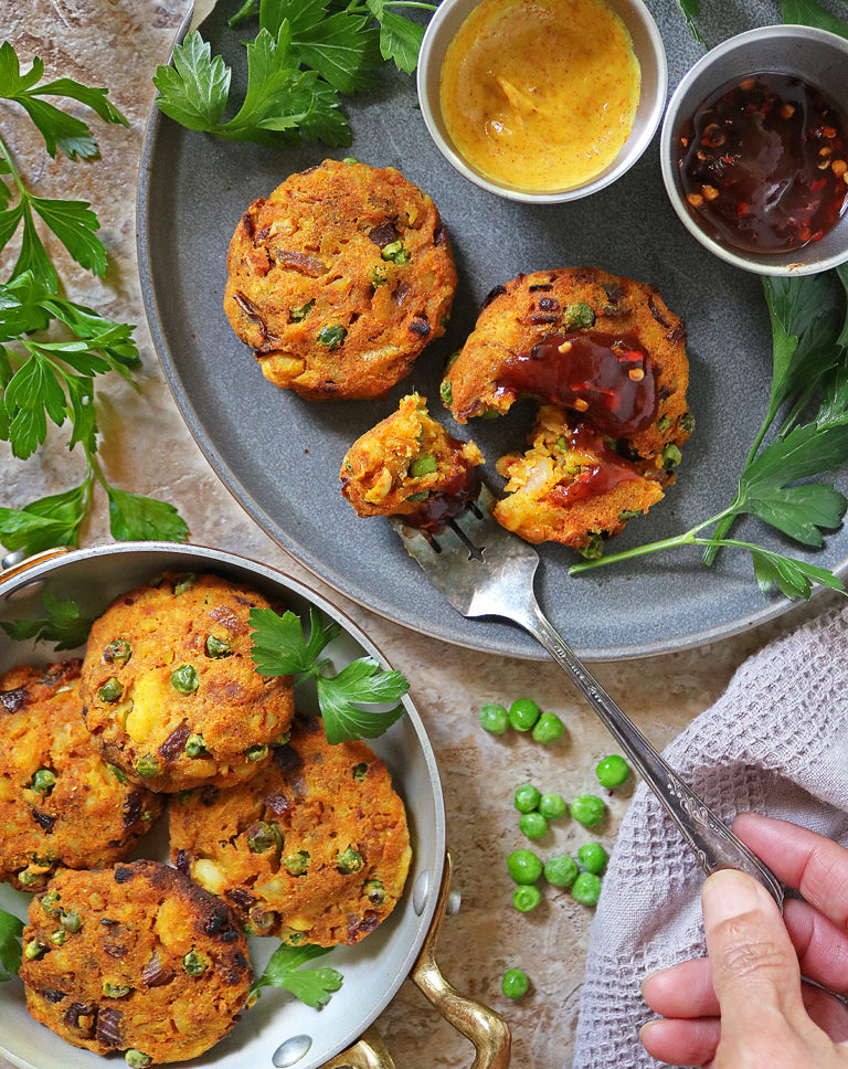 Air fried green pea patties on a plate and some in a serving dish, with parsley around.