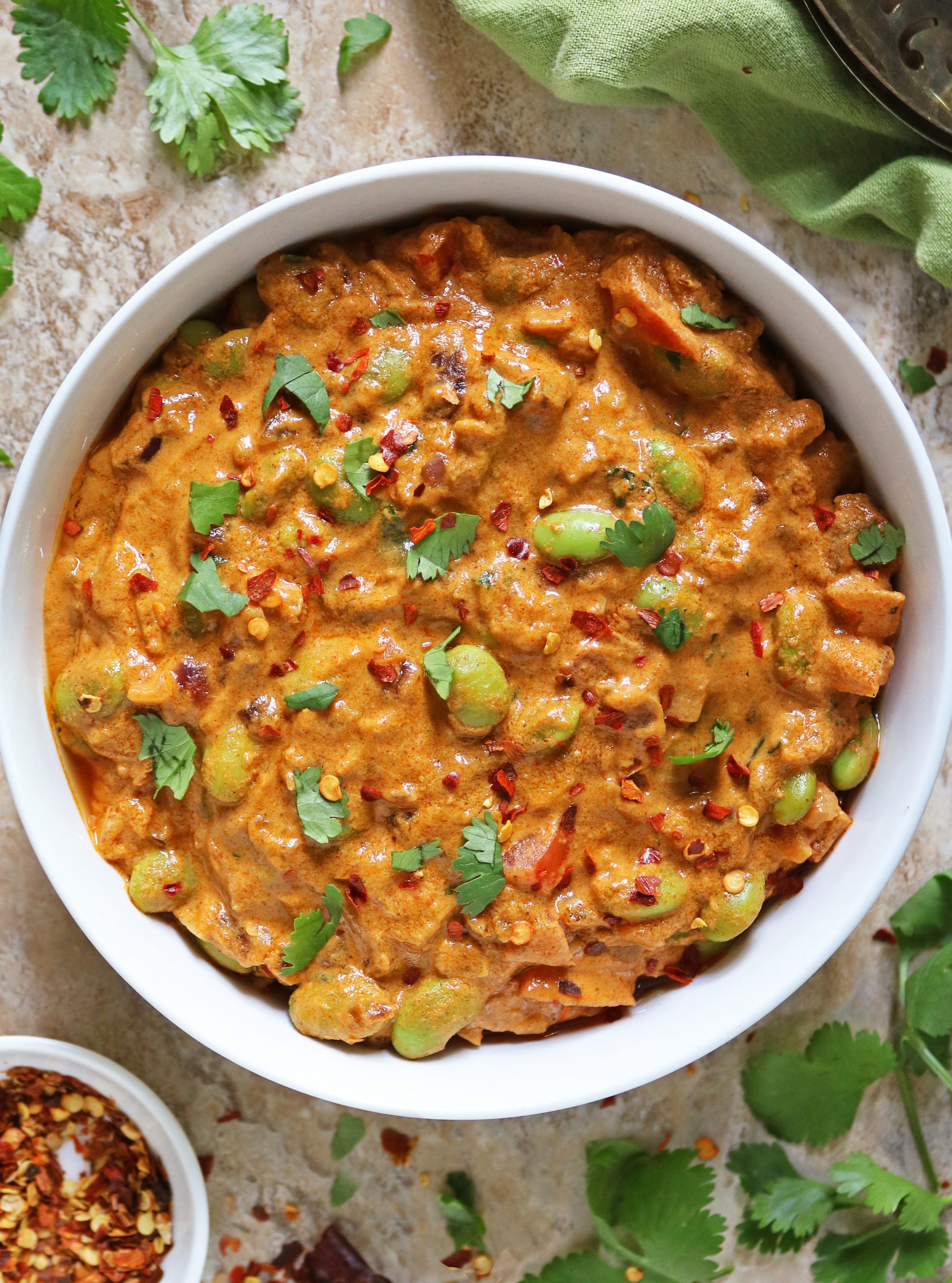 Overhead view of this Easy Edamame curry garnished with parsley and red pepper flakes in a large white bowl.