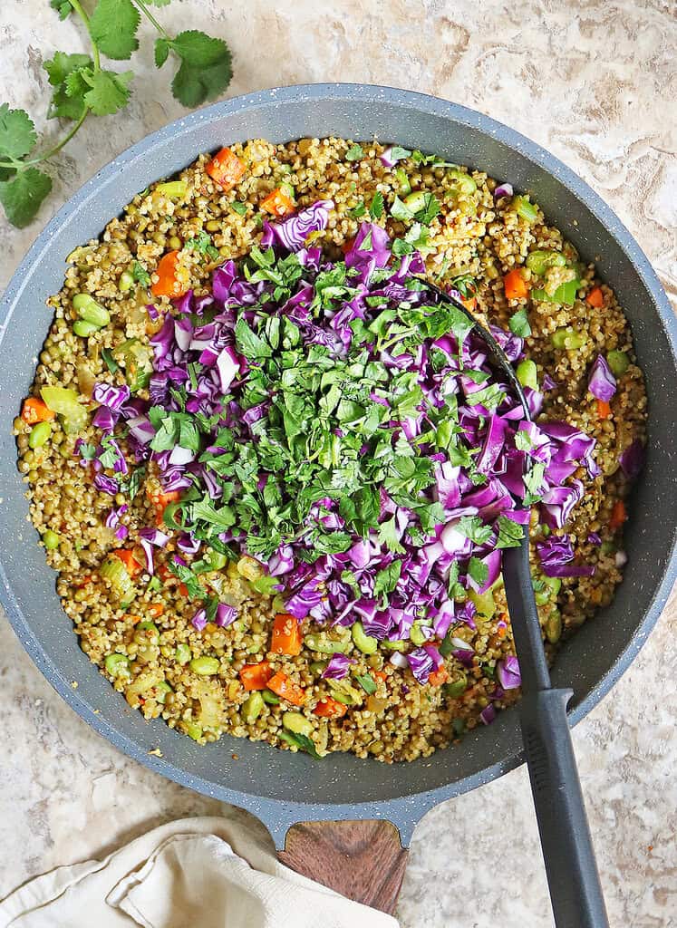 Mixing the cabbage and cilantro with mung bens, quinoa, veggies together