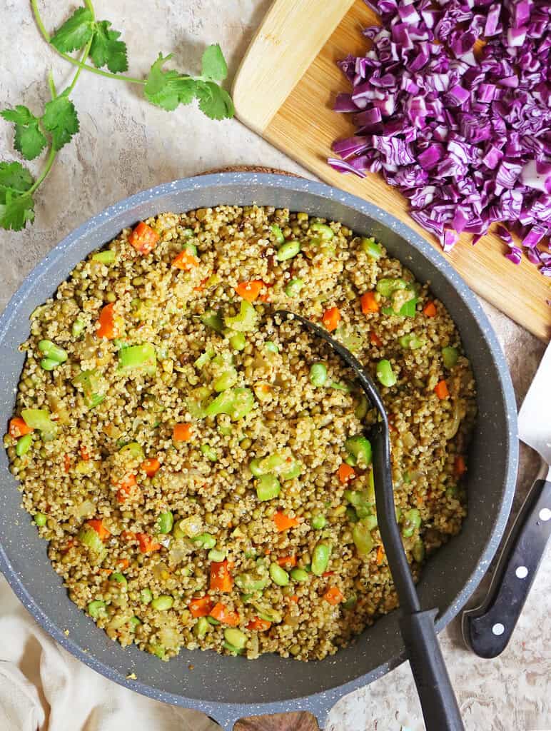 Mixing the moong bens, quinoa, veggies together in large skillet.