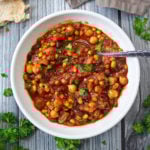 Slow Cooker Vegetarian Three Bean Stew in a white bowl with a spoon in it.
