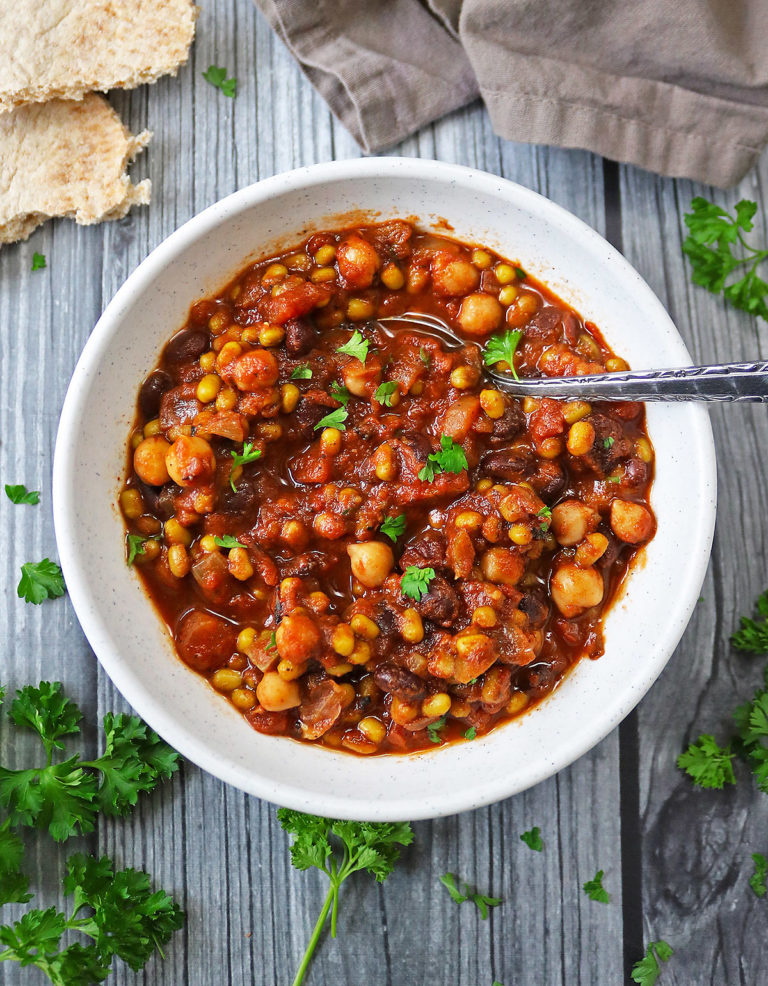 Slow Cooker Vegetarian Three Bean Stew in a white bowl with a spoon in it.