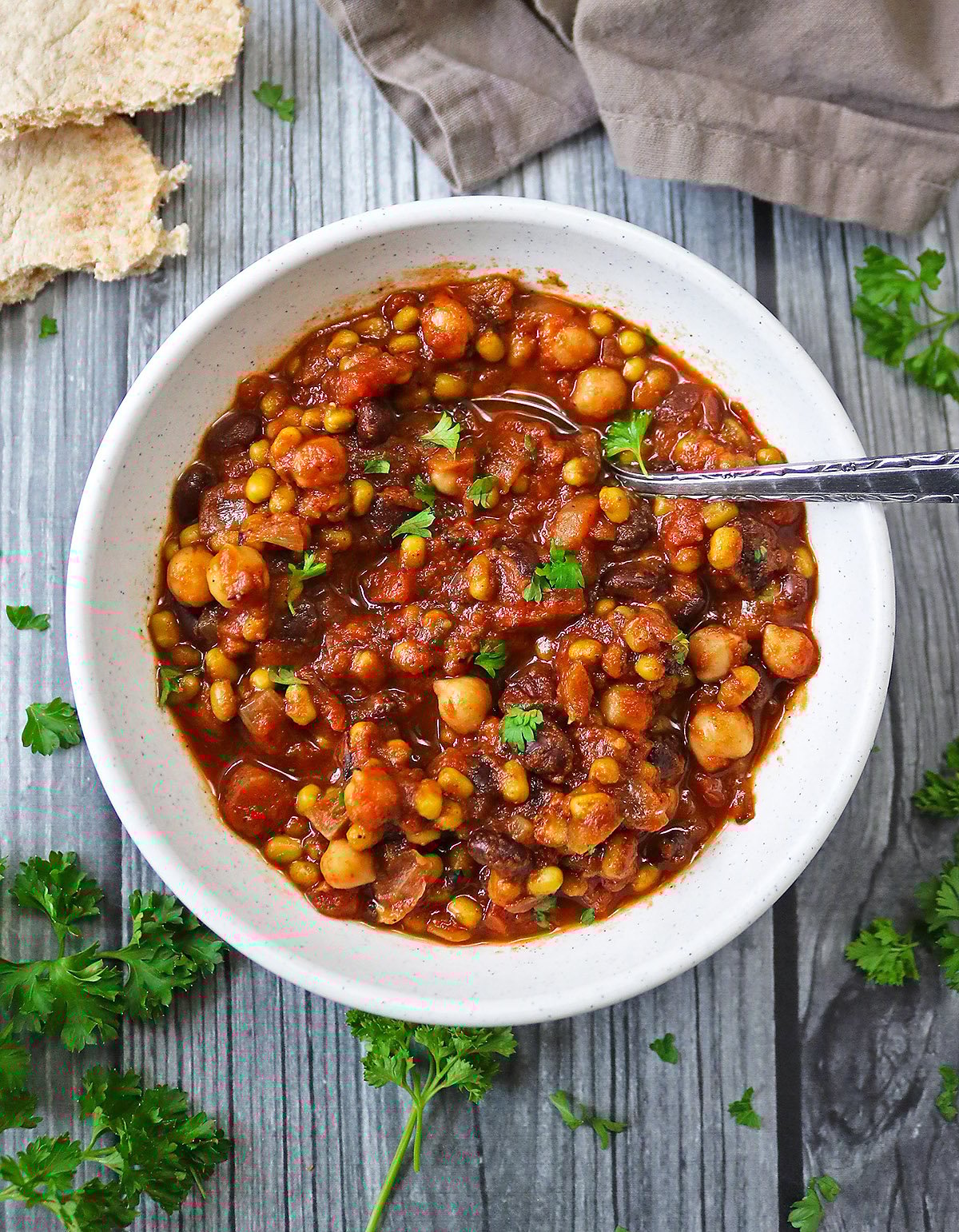 Slow Cooker Vegetarian Three Bean Stew in a white bowl with a spoon in it.
